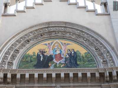 Al centro della facciata tre ampi archivolti dentati, vegetali e con sculture di angioletti racchiudono un lunettone a mosaico raffigurante Nostra signora del sacro cuore tra angeli e santi benedettini oranti